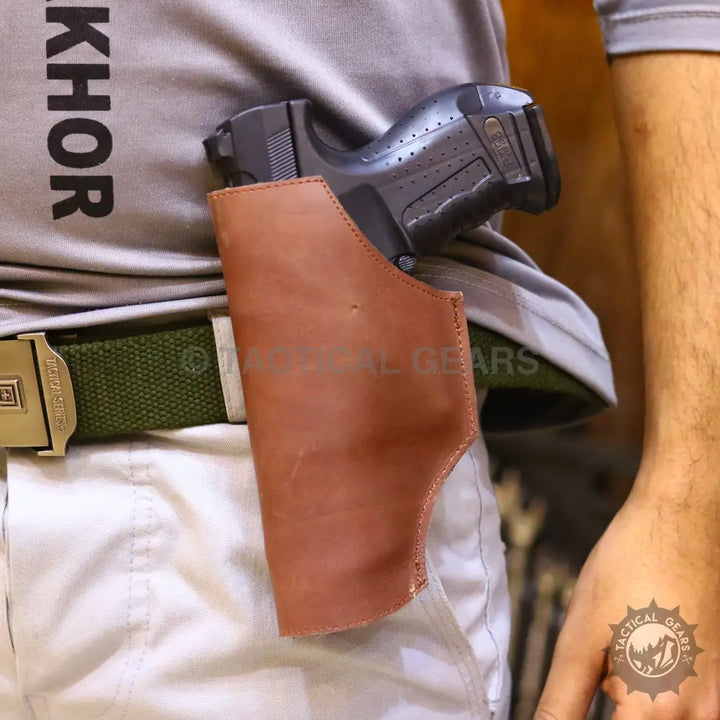 Black handgun in a brown leather belt holster on a green web belt for universal belt holster