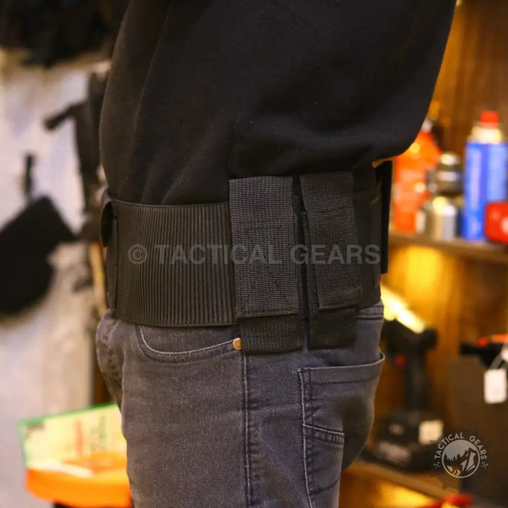 Black tactical belt with attached pouches worn by a person in blue jeans for essentials
