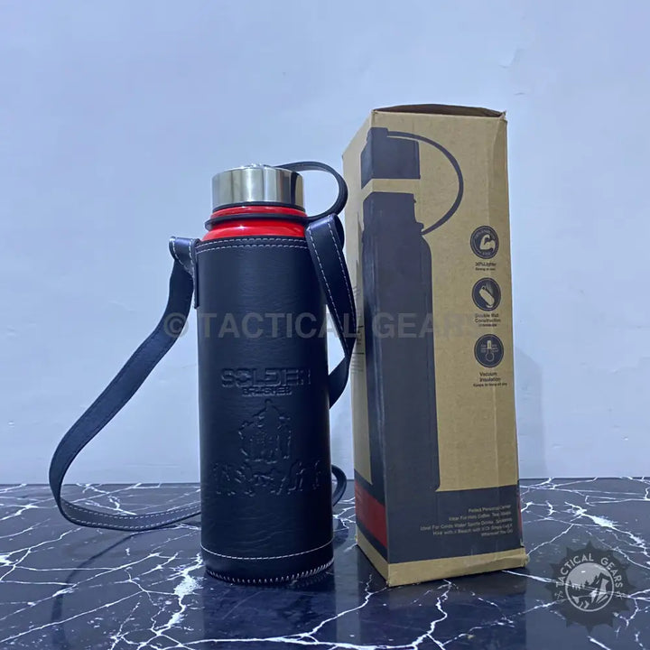 Red vacuum bottle with leather cover and shoulder strap, next to its cardboard packaging