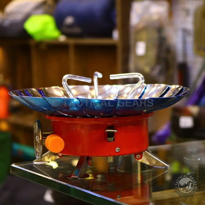 Red and silver Windshield Lotus Camping Stove with blue wind shield for outdoor cooking